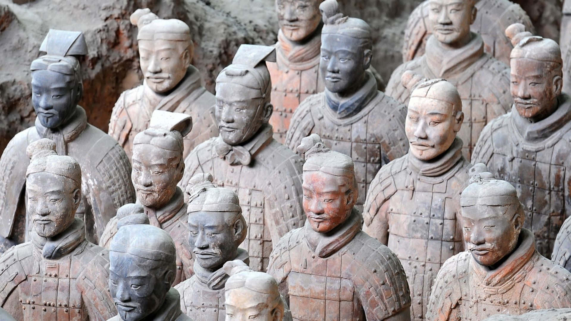 中國博物館內的秦俑石雕細節 壁紙 — 一排排古代兵馬俑莊嚴地矗立在發掘坑中，帶有泥土色調和風化的盔甲。