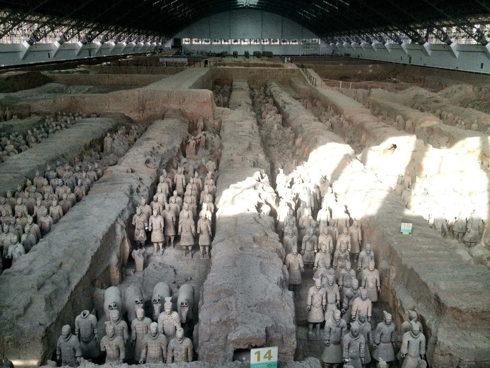 中國博物館內的秦始皇陵陶俑 壁紙 — 一排排古代兵馬俑在現代保護屋頂下，於廣闊的考古發掘現場中整齊排列。