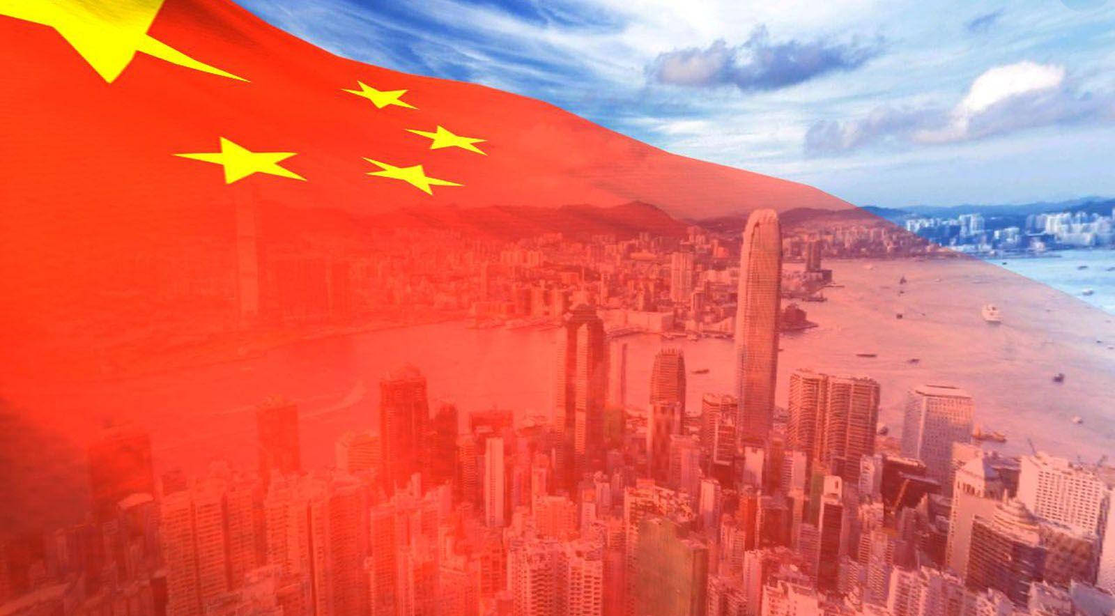 中國國旗城市鳥瞰 壁紙 — 一幅廣闊的鳥瞰圖，密集的城市天際線覆蓋著一面飄揚的大型中國國旗。