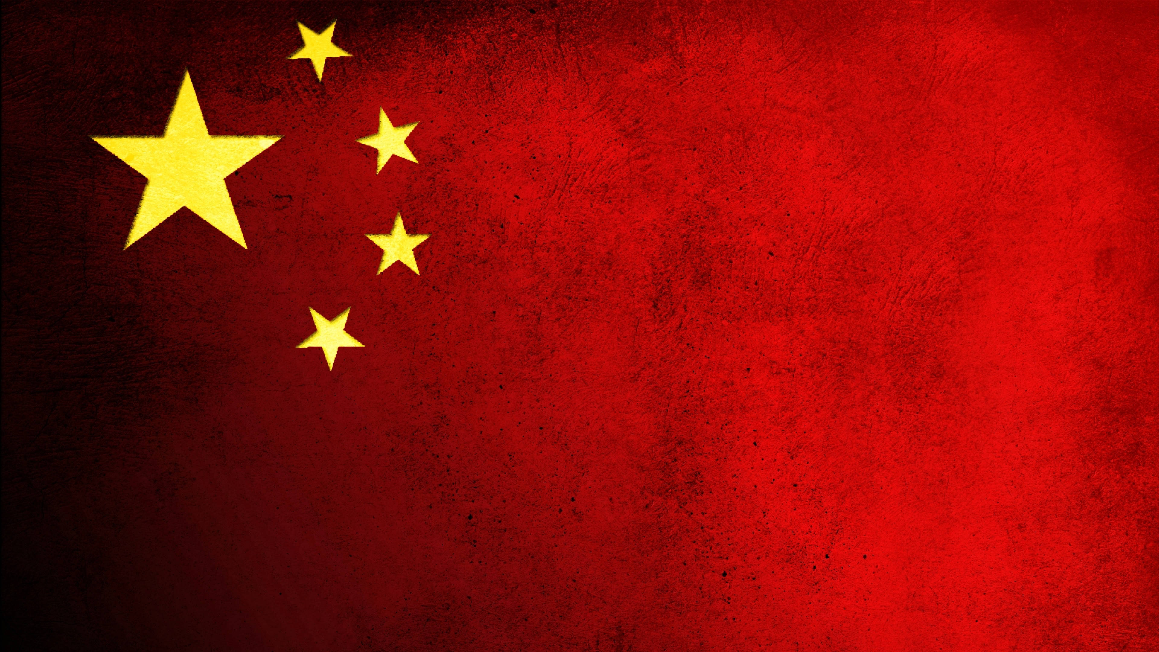 中國國旗帶黑點 壁紙 — 一面風化的中國國旗，帶有鮮明的紅色布料和黃色星星，顯示出可見的紋理和褪色。