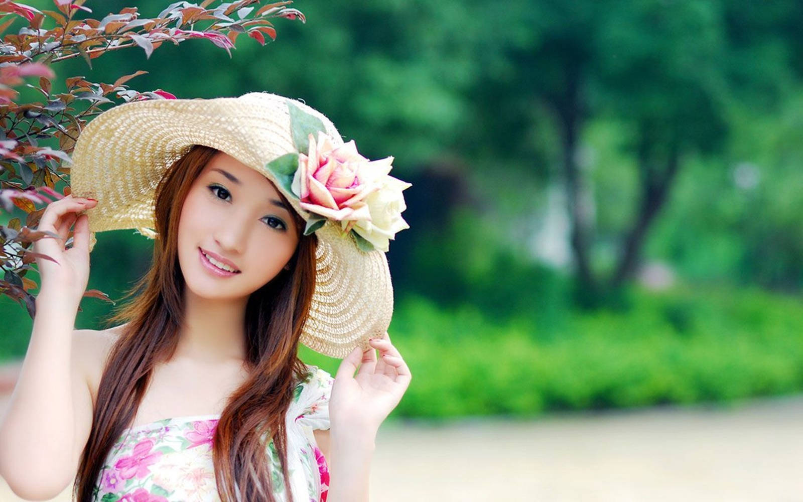 穿著花卉圖案連衣裙和草帽的年輕女子在花園中微笑。