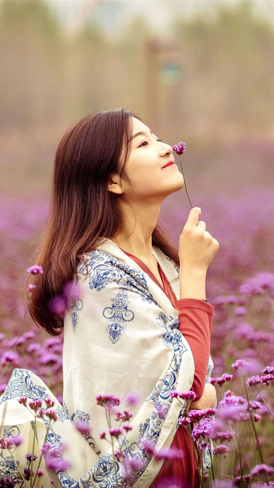 身穿圖案長袍的女性在田野中聞紫色花
