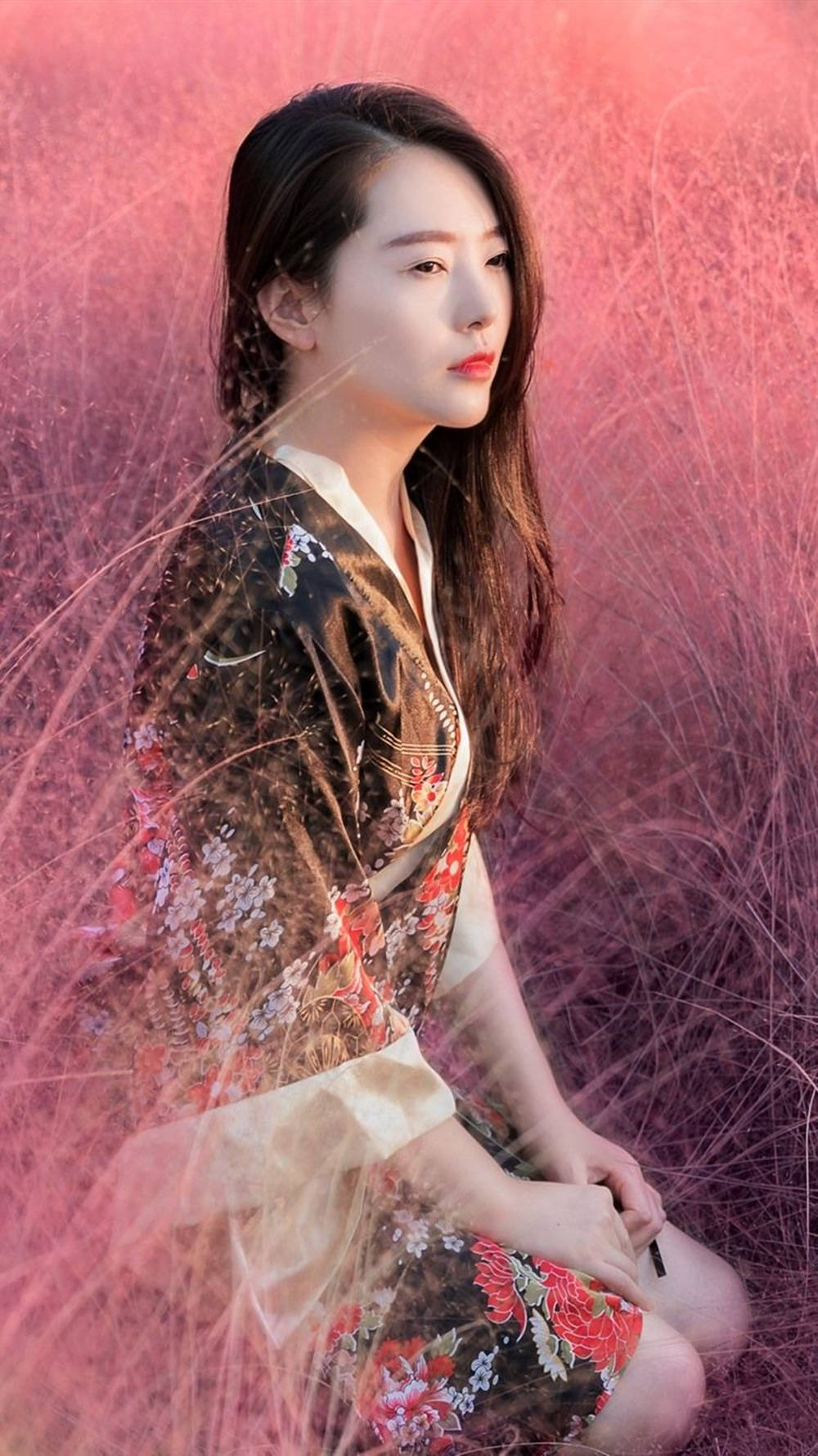 身穿花卉和服的女士坐在粉紅色草地上