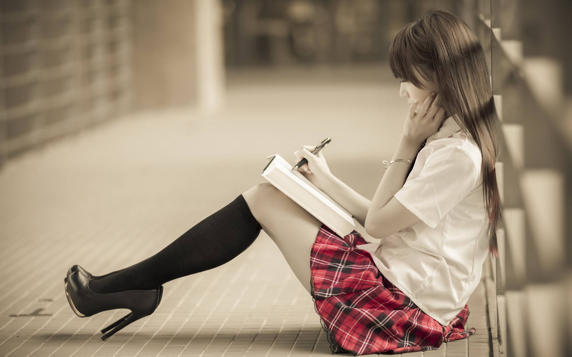 一名穿著校服的女孩坐在瓷磚地上在筆記本上寫字。