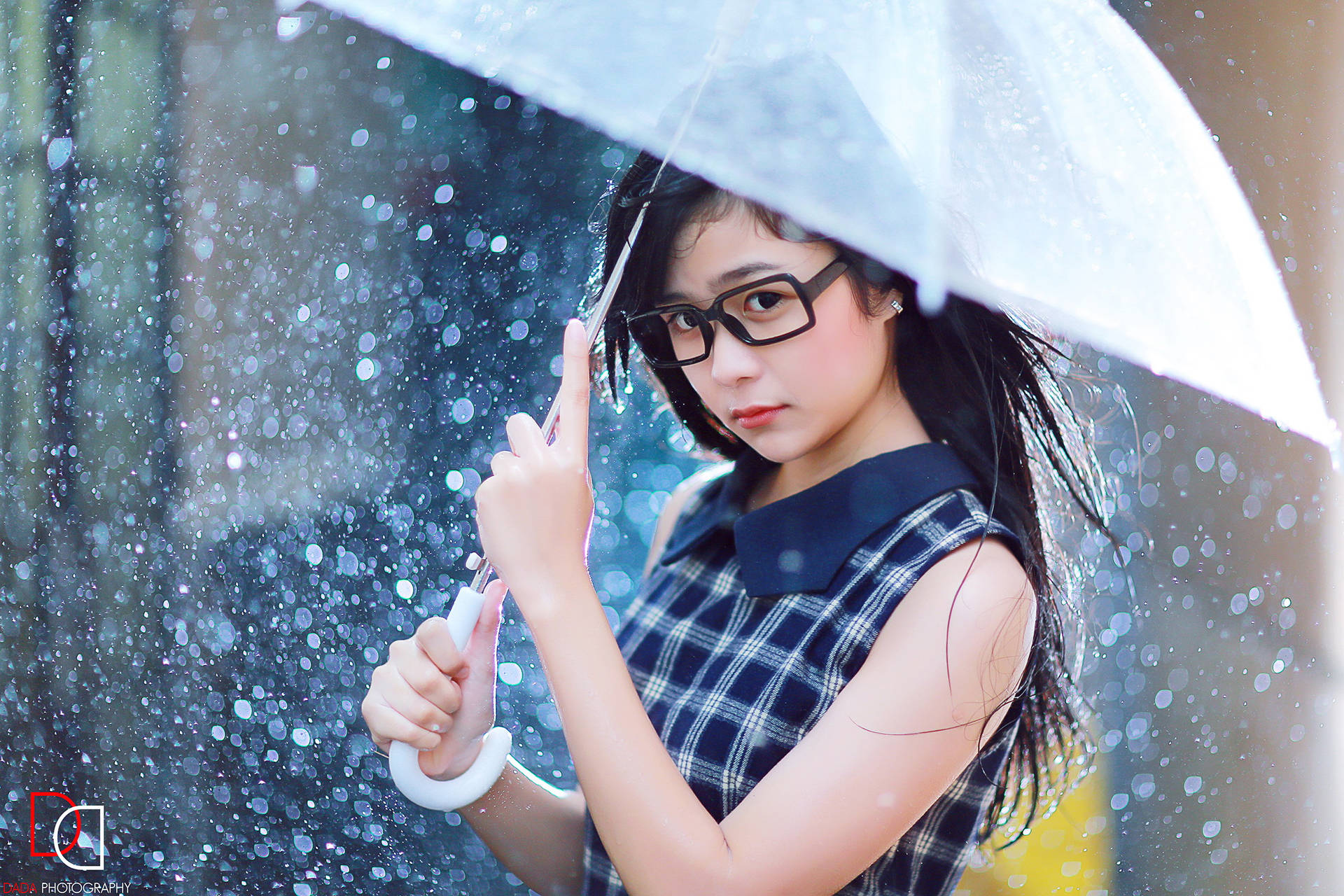戴眼鏡的女孩在雨中城市環境中拿著透明雨傘