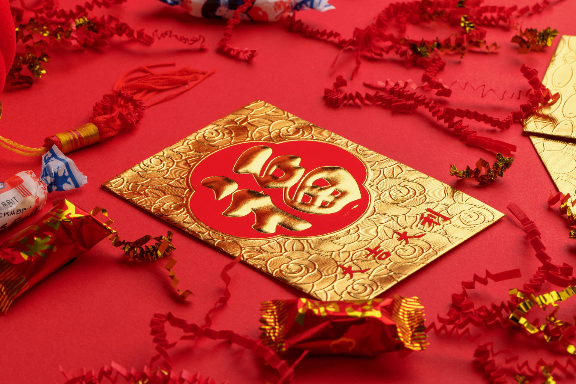帶有金色中文字的紅包，周圍是喜慶的紙屑和糖果。