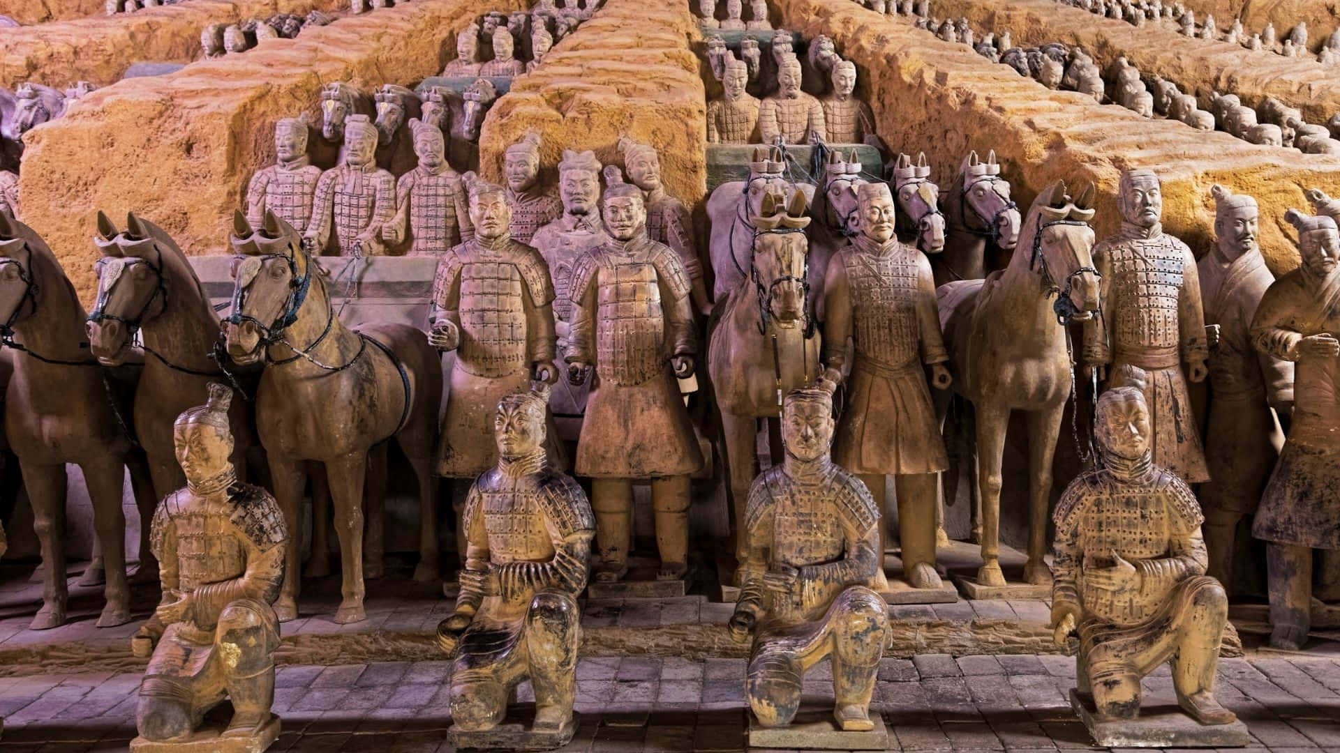 中國歷史兵馬俑博物館 壁紙 — 一排排古老的兵馬俑在溫暖的燈光下，於考古發掘現場整齊排列。