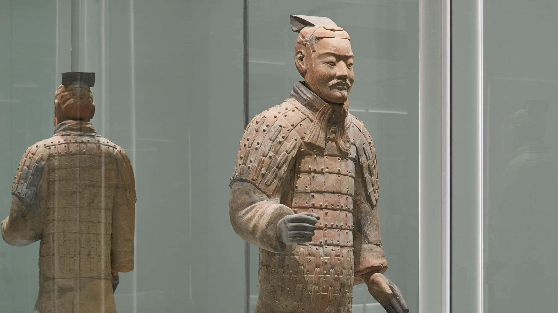 中國秦始皇陵陶俑博物館 壁紙 — 一個身穿精細盔甲的兵馬俑雕像站立在玻璃展示櫃中，其倒影在後方清晰可見。