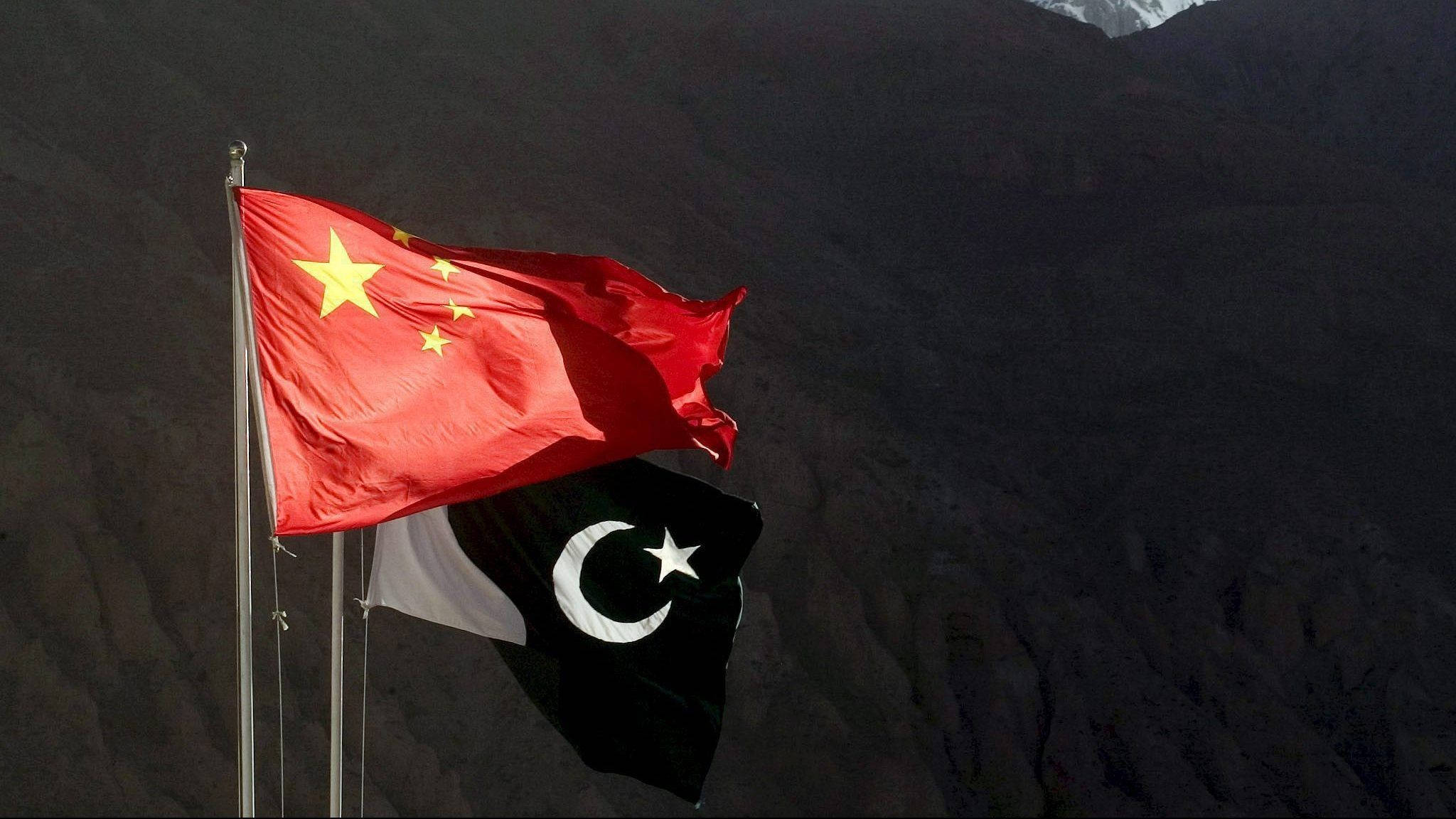 中國與巴基斯坦國旗 壁紙 — 中國和巴基斯坦國旗在明亮的日光下，以崎嶇的山脈為背景並排飄揚。