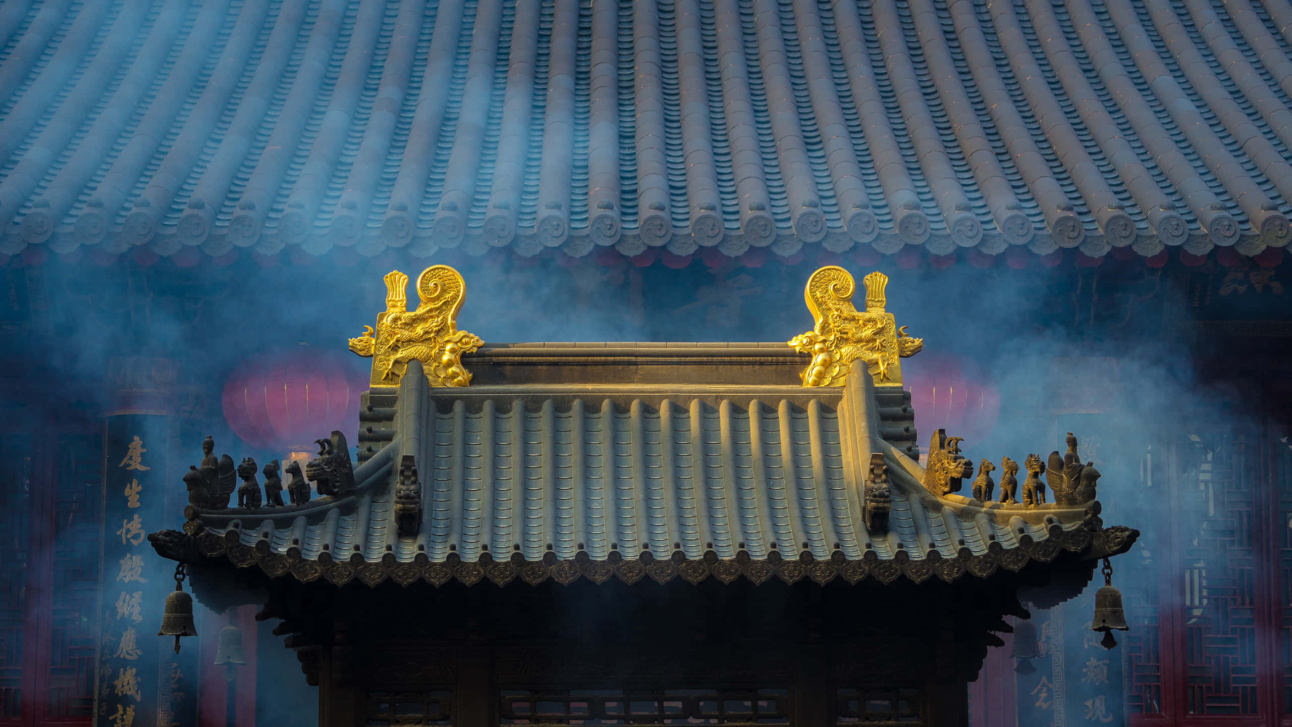 中國長江的湛藍水域 壁紙 — 傳統中式寺廟屋頂，飾有金色龍形裝飾和藍色瓦片，籠罩在煙霧繚繞和柔和光線中。