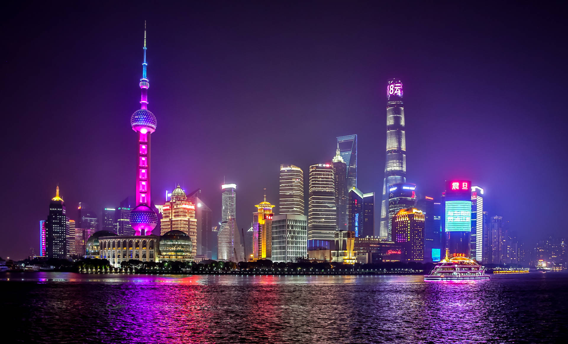 夜晚的上海天際線，燈火通明的塔樓和河流倒影。