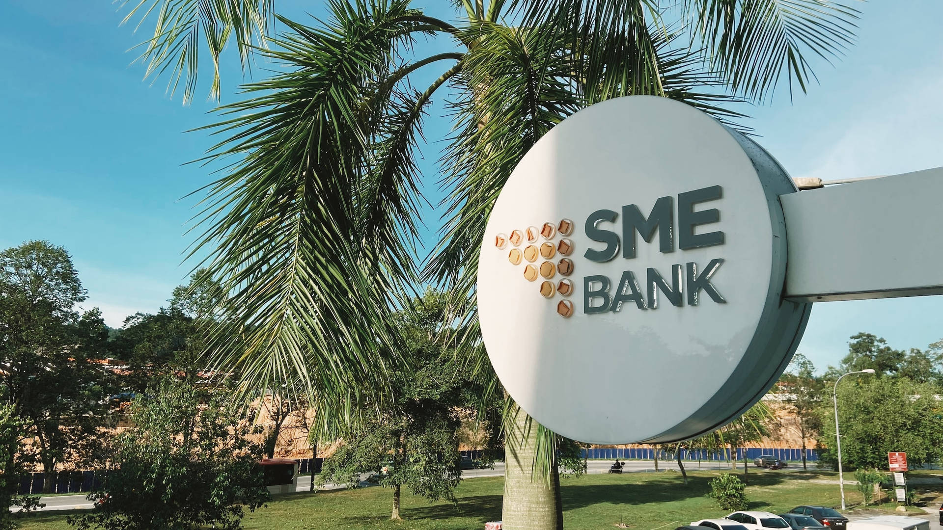 SME Bank標誌被棕櫚樹和綠植環繞，背景是晴朗的藍天。