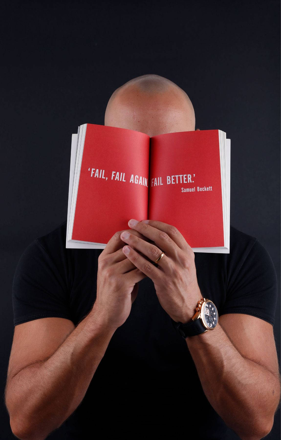 男人拿著打開的紅色書，上面有引文 fail fail again fail better