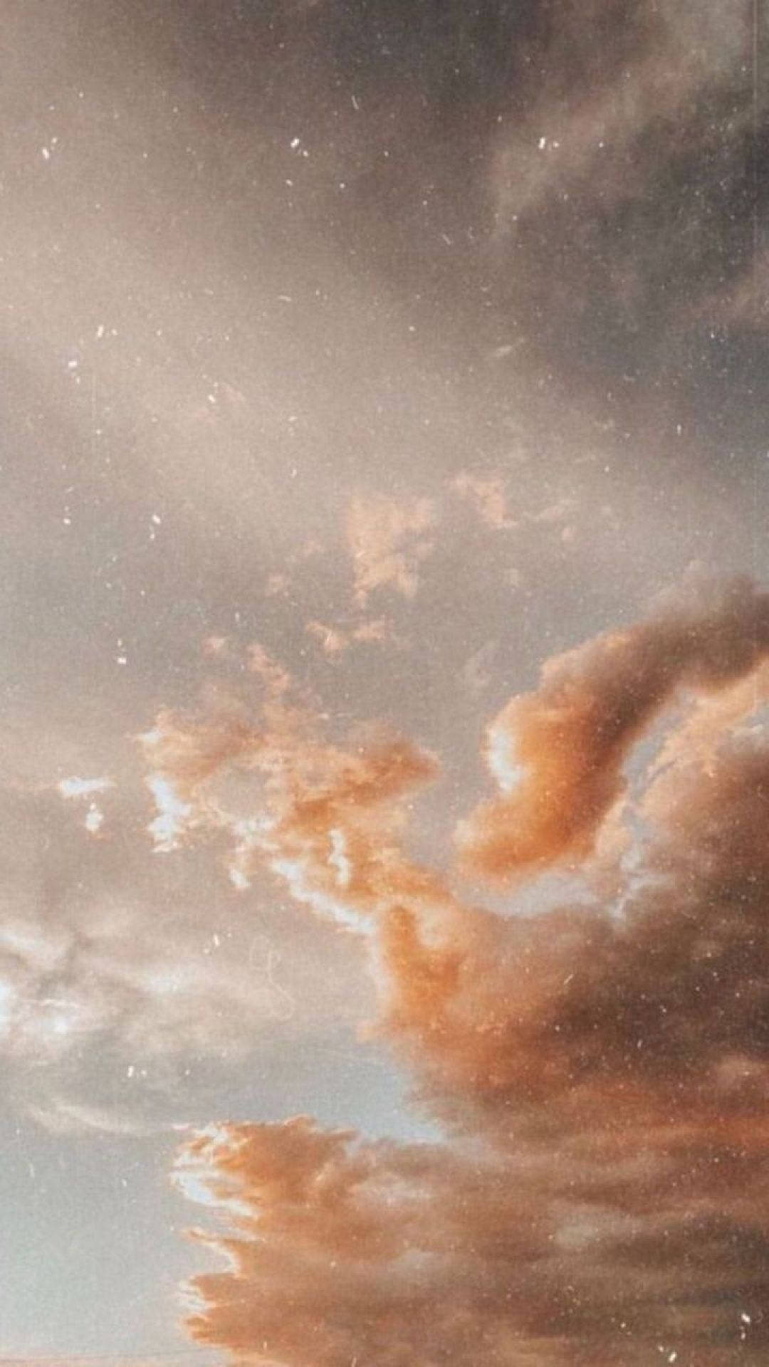 在朦朧的天空中柔和發光的戲劇性橙色和灰色雲層。