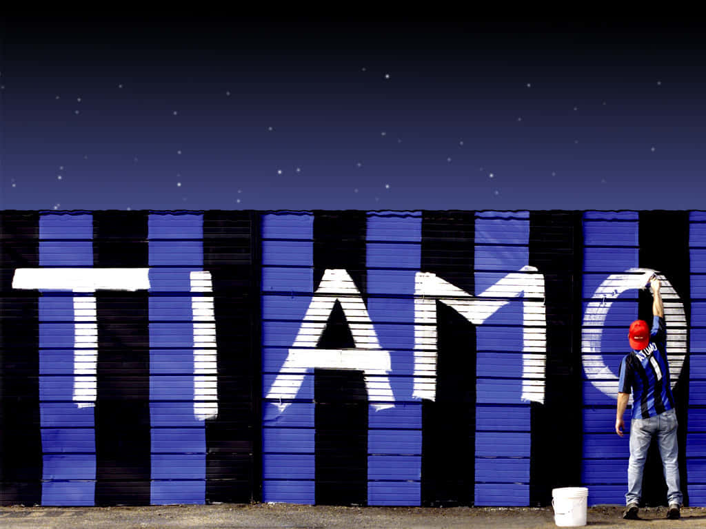 藝術家在星空下的藍黑條紋牆上塗寫「TIAMO」。