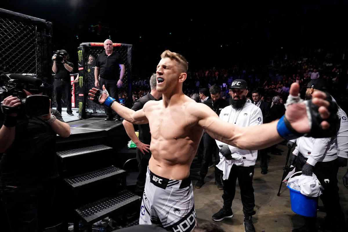 UFC拳手在八角籠中伸展雙臂慶祝勝利。