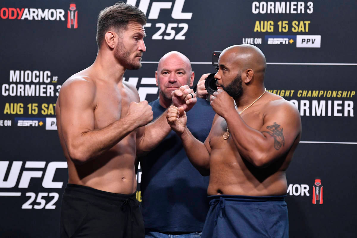 丹尼爾·科爾米爾與斯蒂普·米奧奇 UFC 252 壁紙 — 兩位肌肉發達的UFC拳手在稱重活動中鎖拳進行緊張的賽前對視。