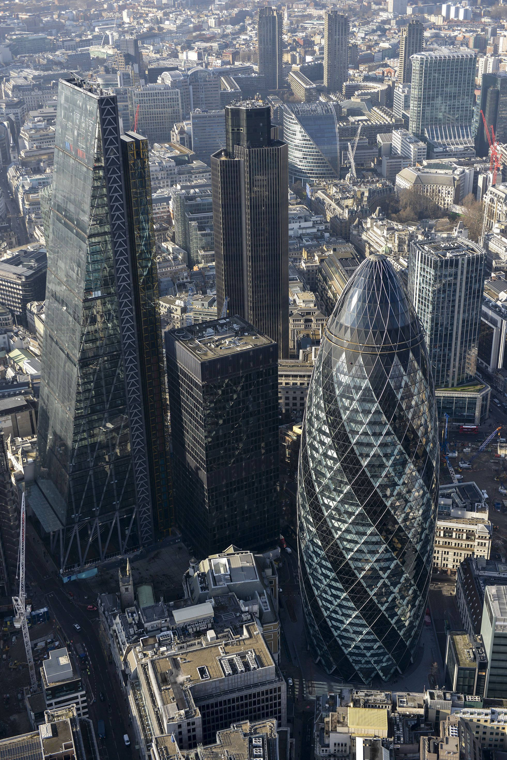 主宰倫敦天際線的Gherkin大樓 壁紙 — 倫敦金融區的鳥瞰圖，展示了標誌性的現代摩天大樓，如小黃瓜大廈和對講機大廈，背景是密集的城市建築。