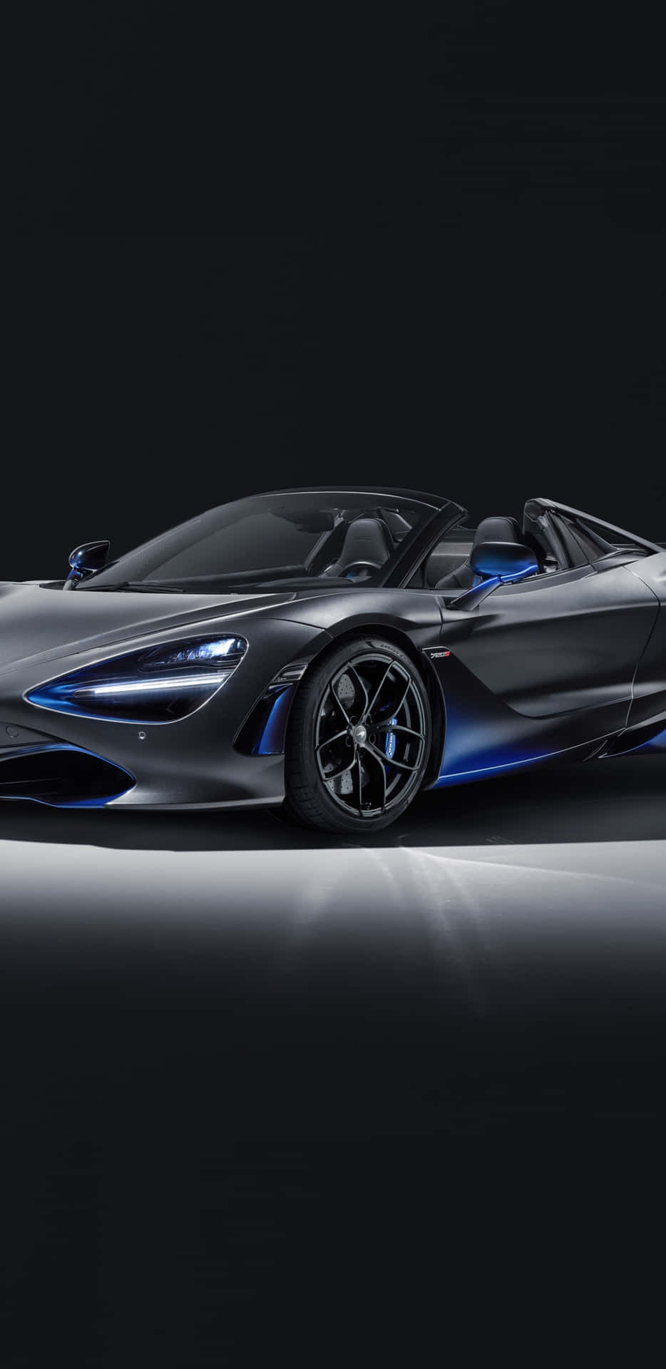在工作室聚光燈下，時尚的灰色McLaren 720S Spider帶有藍色飾邊。 — 主螢幕 壁紙