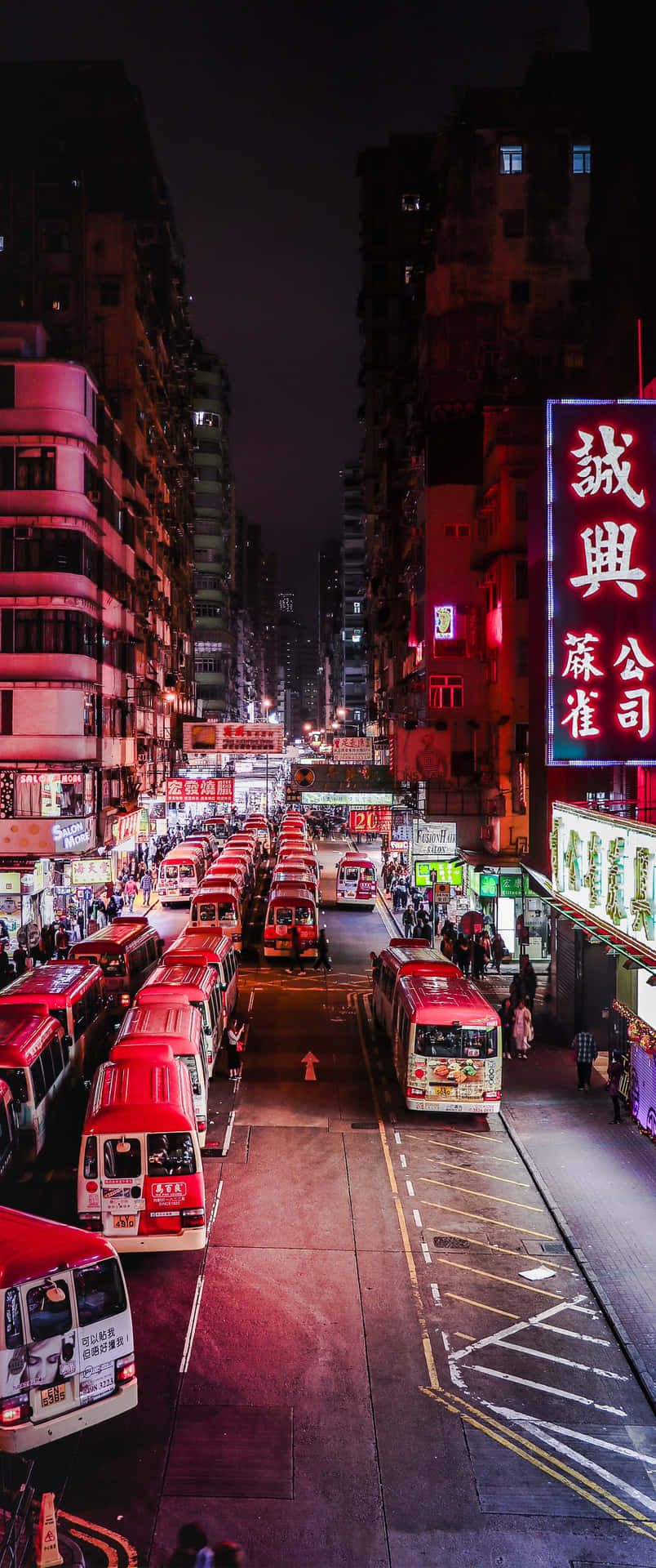 夜晚的城市街道，有紅色巴士和閃爍的霓虹燈牌。