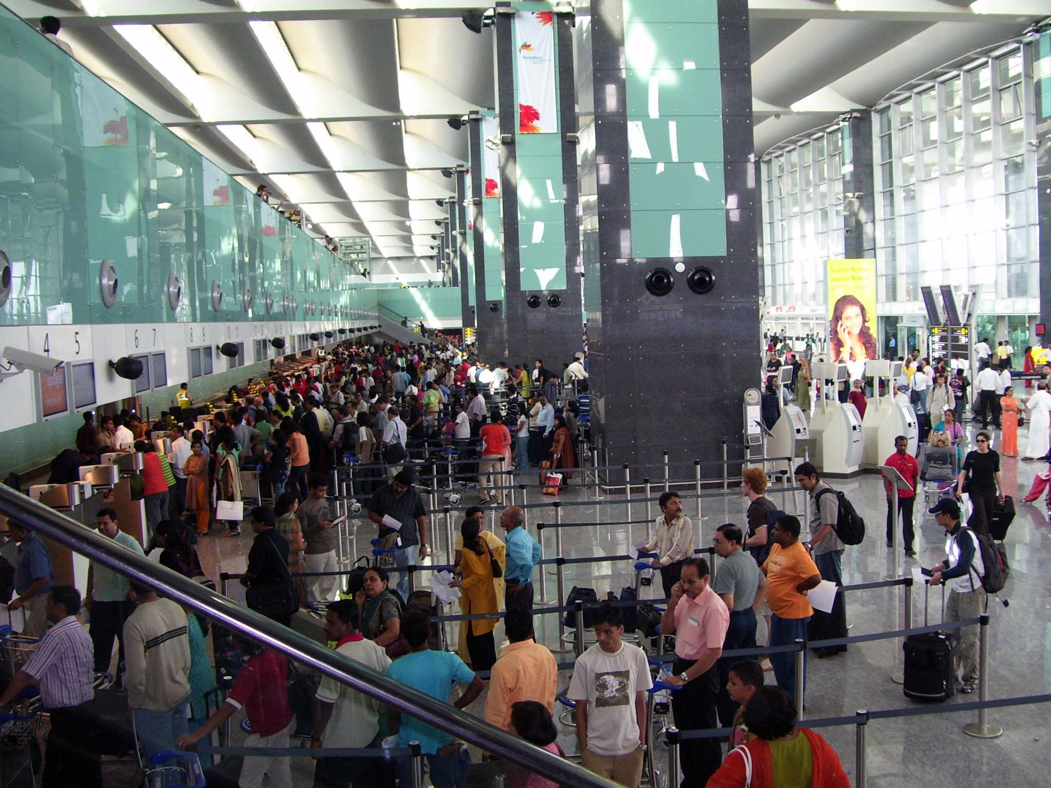 乘客在肯佩戈瓦達機場 壁紙 — 擁擠的機場客運大樓，旅客在明亮的螢光燈下排隊等候辦理登機手續。