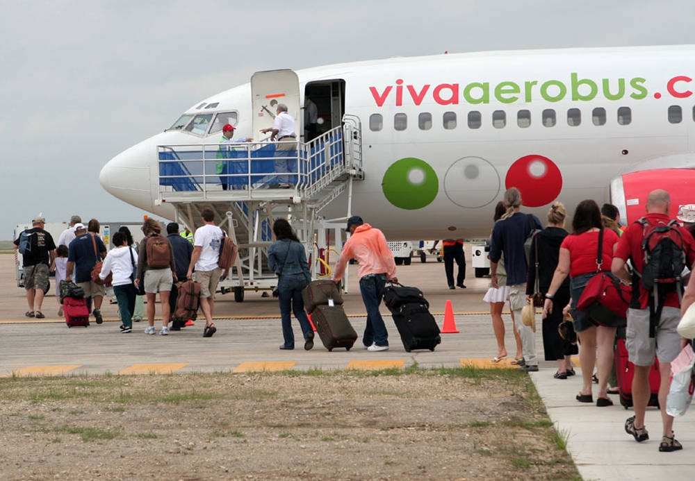 旅客帶著行李箱在陰天登上Viva Aerobus飛機。