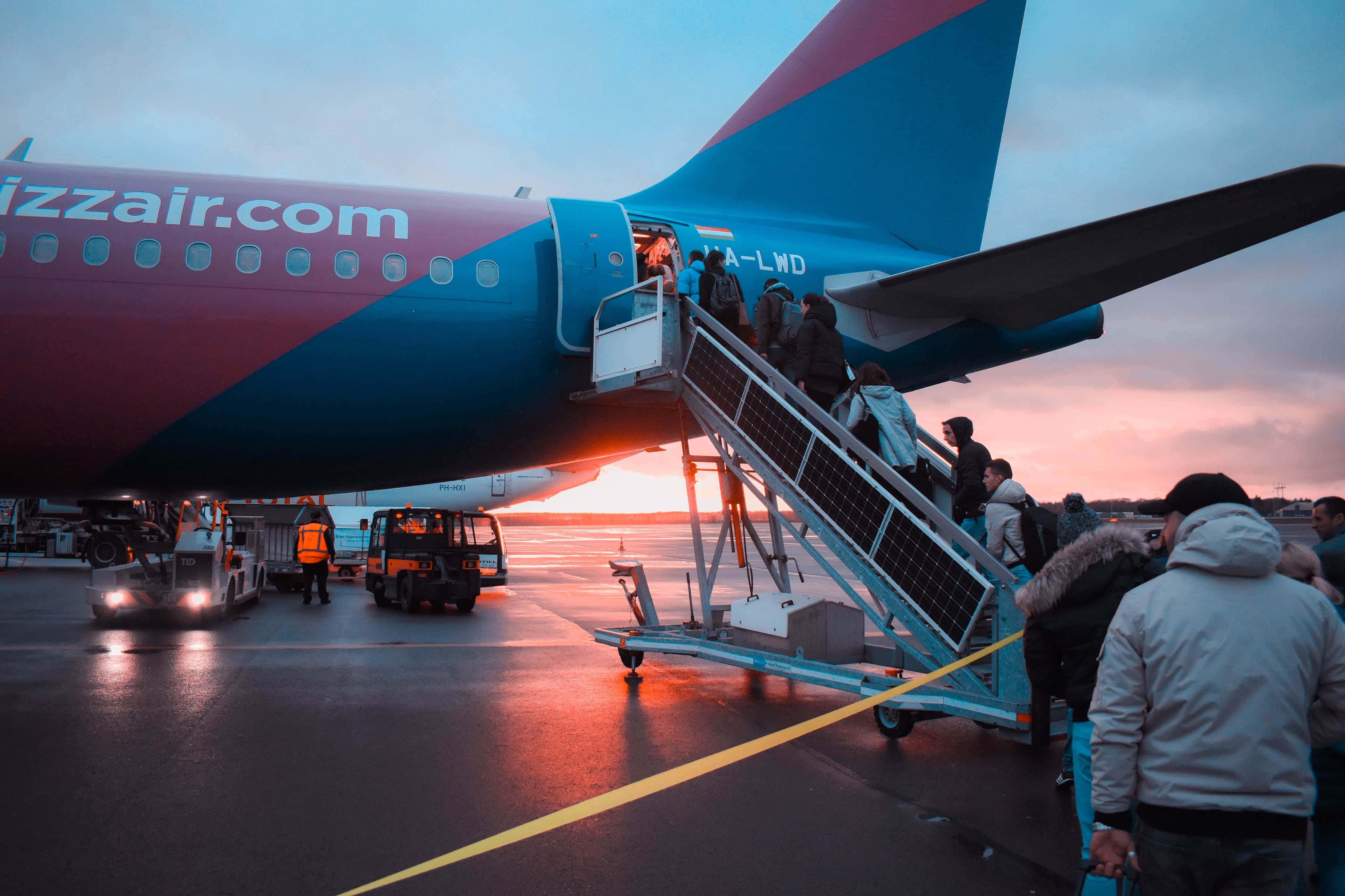Airport 桌布 壁紙 — 乘客經樓梯登上色彩繽紛的西南航空飛機，夕陽正落在濕漉漉的停機坪上。