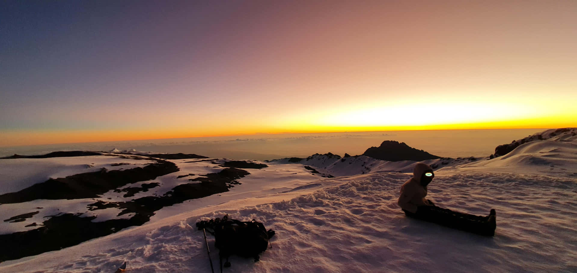 遠足者在日出時在白雪覆蓋的山頂上休息