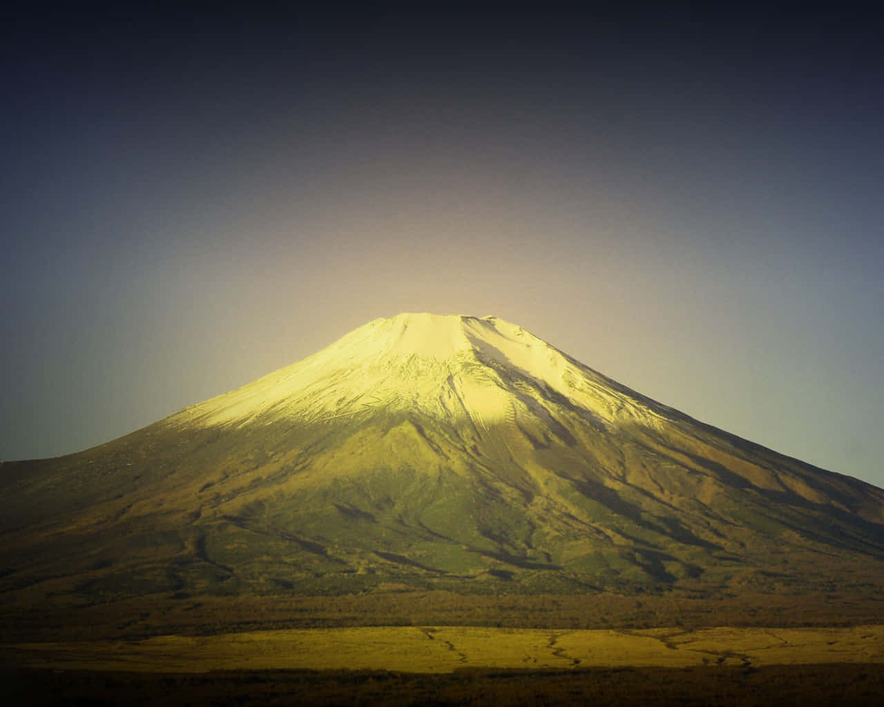 富士山被日出照亮，積雪的山頂和漸變色的天空。