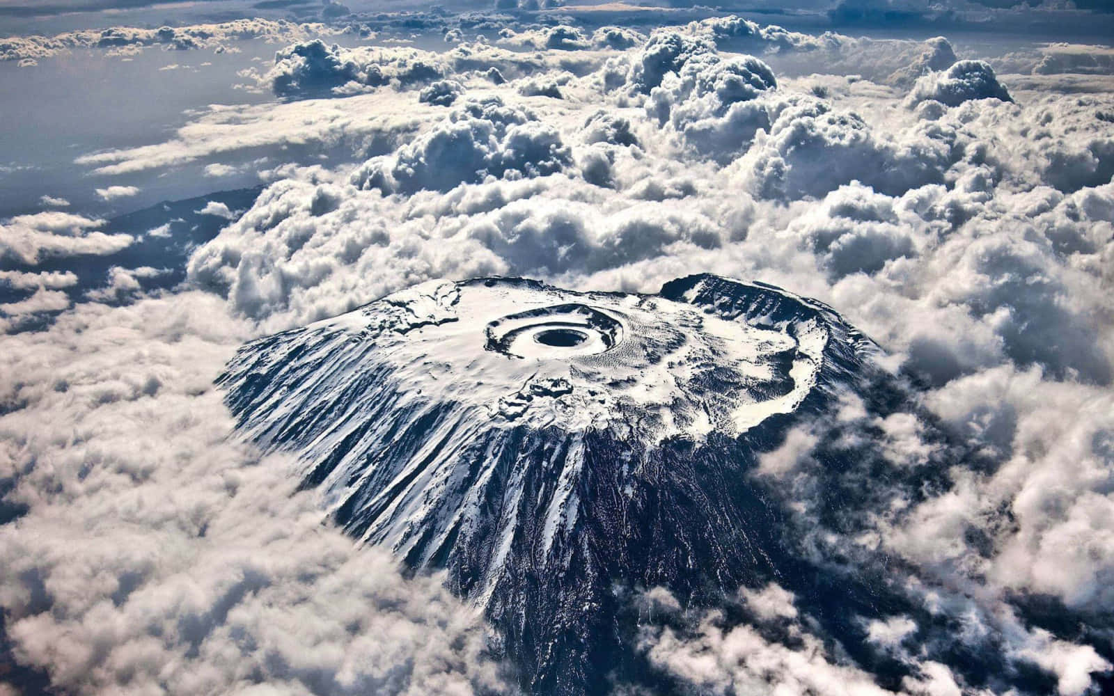 一座積雪覆蓋的火山，其火山口從上方穿透雲層。