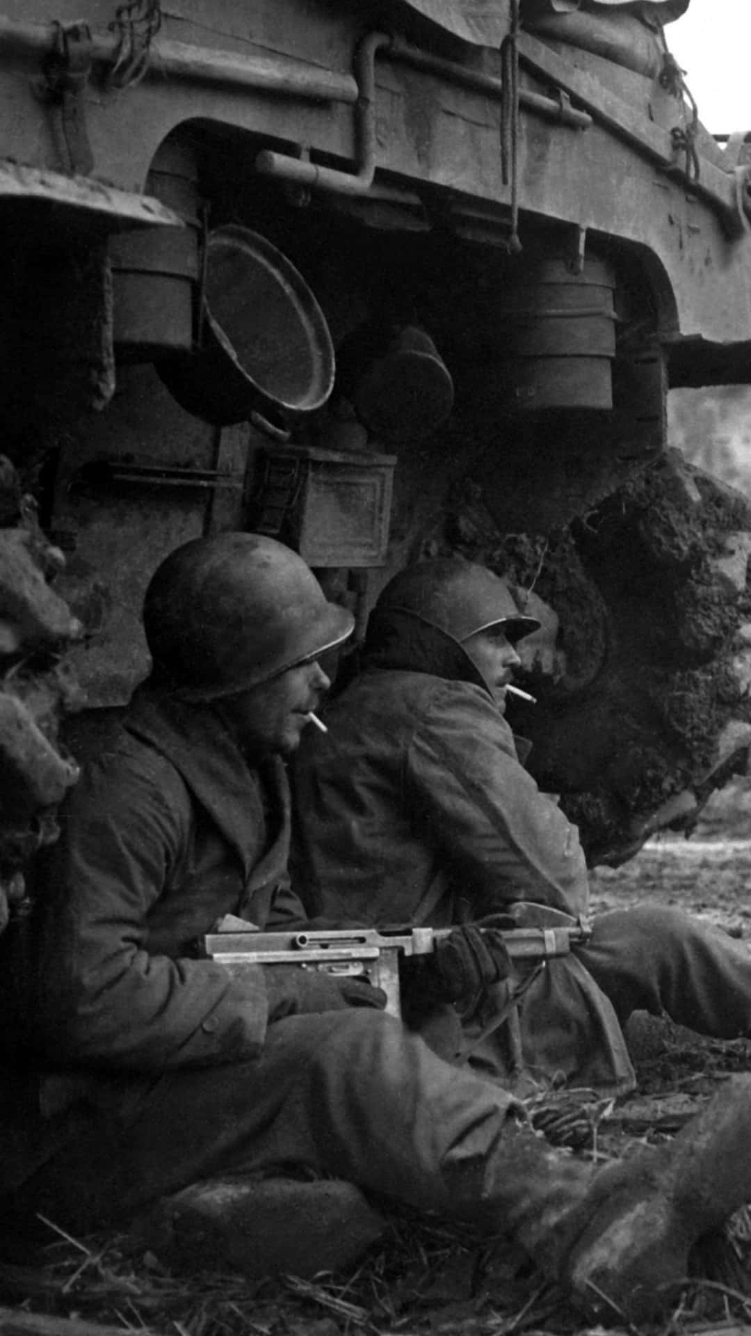 兩名士兵在坦克旁休息，在泥濘的田野上抽煙。