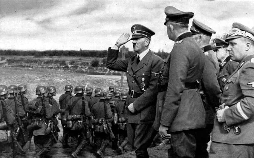 阿道夫·希特拉與戴頭盔的納粹軍官和士兵在戶外敬禮。