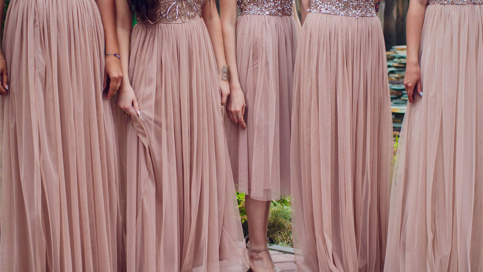 Pink Dress 桌布 壁紙 — 五位伴娘穿著飄逸的淡粉紅色禮服，配以閃亮腰帶，一起站在戶外。