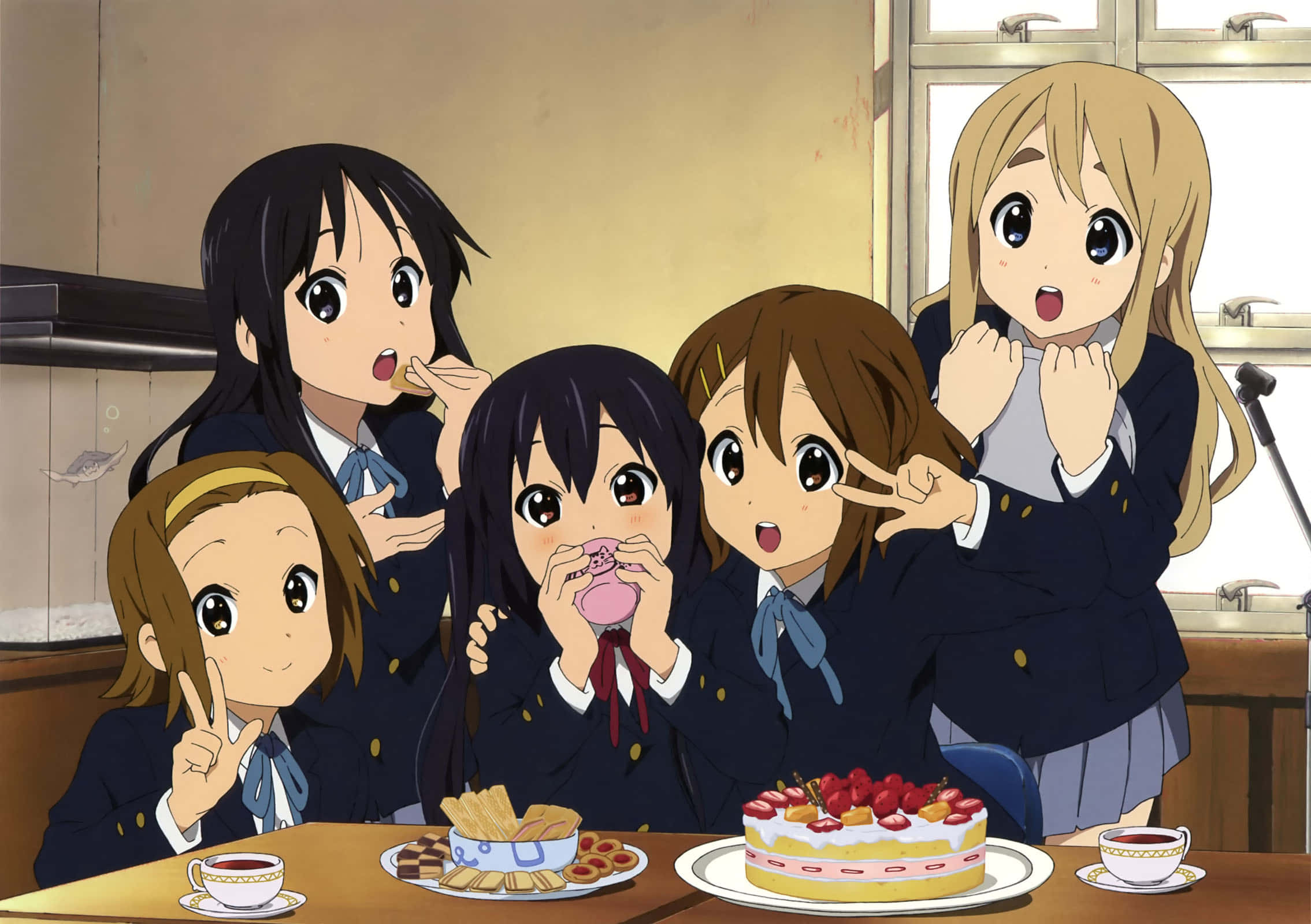 K-on 桌布 壁紙 — 五位穿著校服的動畫女孩在明亮的廚房裡，圍著擺滿蛋糕和零食的桌子歡快地聚在一起。
