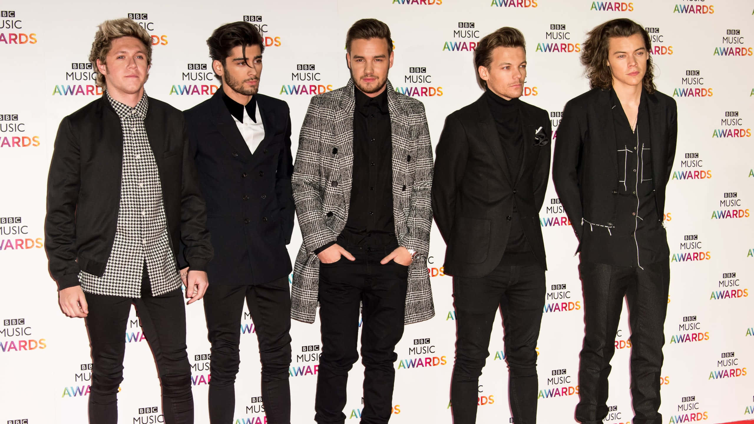 One Direction 桌布 壁紙 — 五位穿著正式服裝的時尚男士在BBC音樂獎品牌背景前自信地擺姿勢。