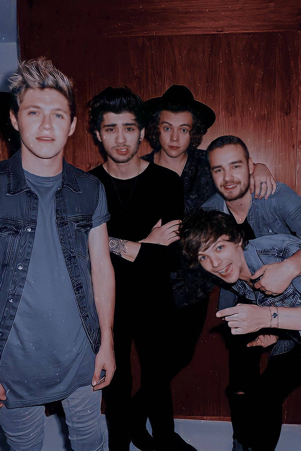 One Direction Aesthetic 桌布 壁紙 — 五位身穿休閒牛仔布和深色衣服的年輕男子，在木牆前擺出俏皮的表情一起合照。