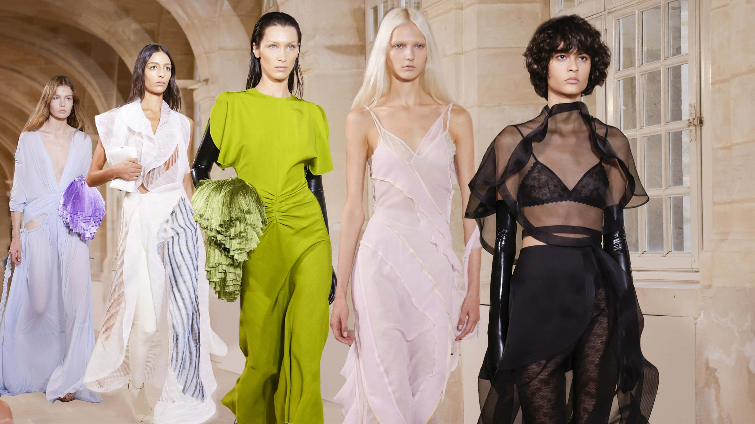 Beautiful Fashion 桌布 壁紙 — 五位身穿前衛時裝的模特兒自信地走過陽光普照的石拱門，穿著大膽的色彩和透明布料。
