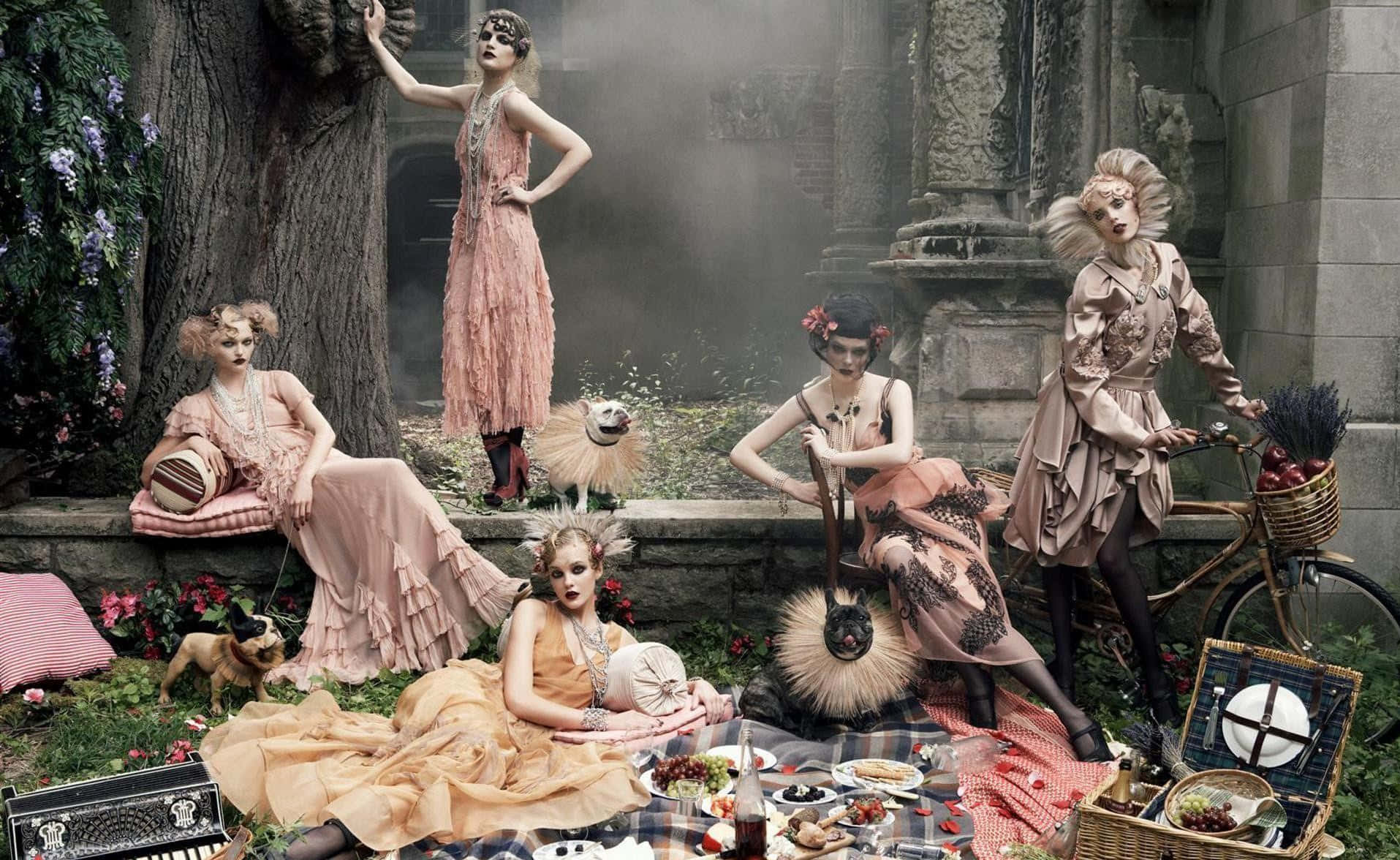 Beauty And Fashion 桌布 壁紙 — 五位身穿復古粉紅色連衣裙的女性在霧氣瀰漫的天空下，在廢墟中與一隻狗和一輛自行車野餐。
