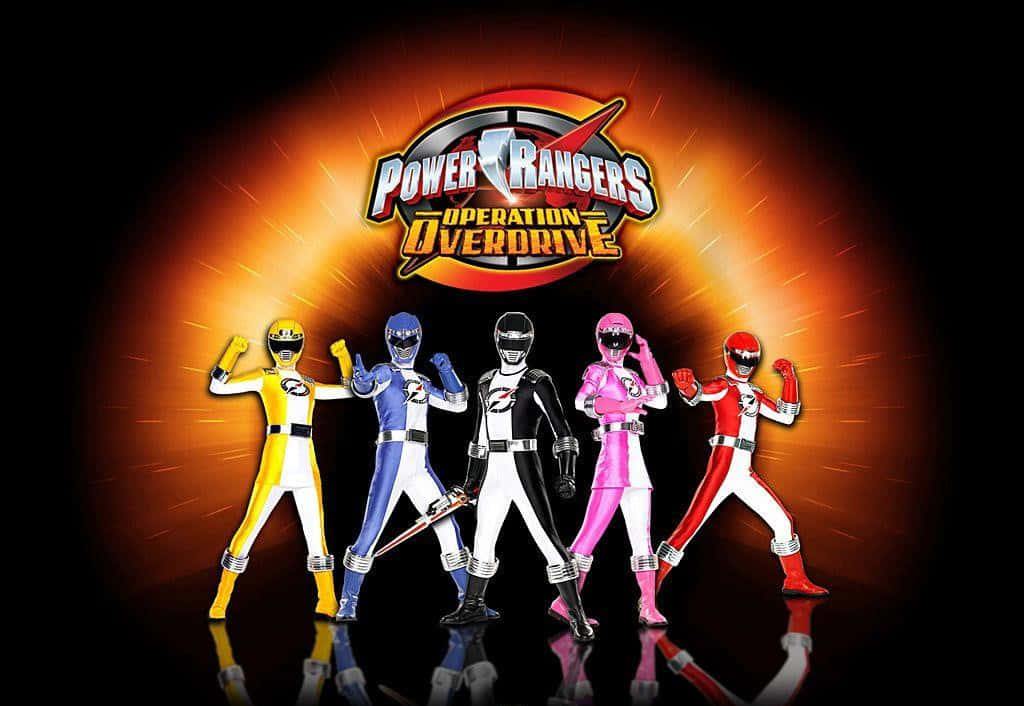 Power Rangers 桌布 壁紙 — 五位身穿黃色、藍色、黑色、粉紅色和紅色戰衣的Power Rangers，在發光的橙色背景前英勇站立，上方有'Operation Overdrive'標誌。