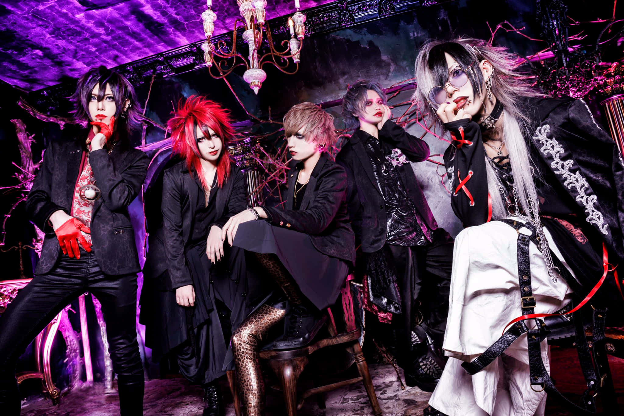 Visual Kei 桌布 壁紙 — 五位風格化的表演者穿著哥德式角色扮演服裝，在一個黑暗華麗的房間裡，在紫色吊燈下戲劇性地擺姿勢。