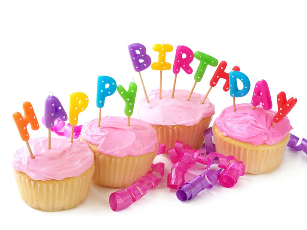 Birthday Wishes 桌布 壁紙 — 五個帶有粉紅色糖霜和彩色字母蠟燭拼出 happy birthday 的杯子蛋糕，周圍環繞著彩帶。