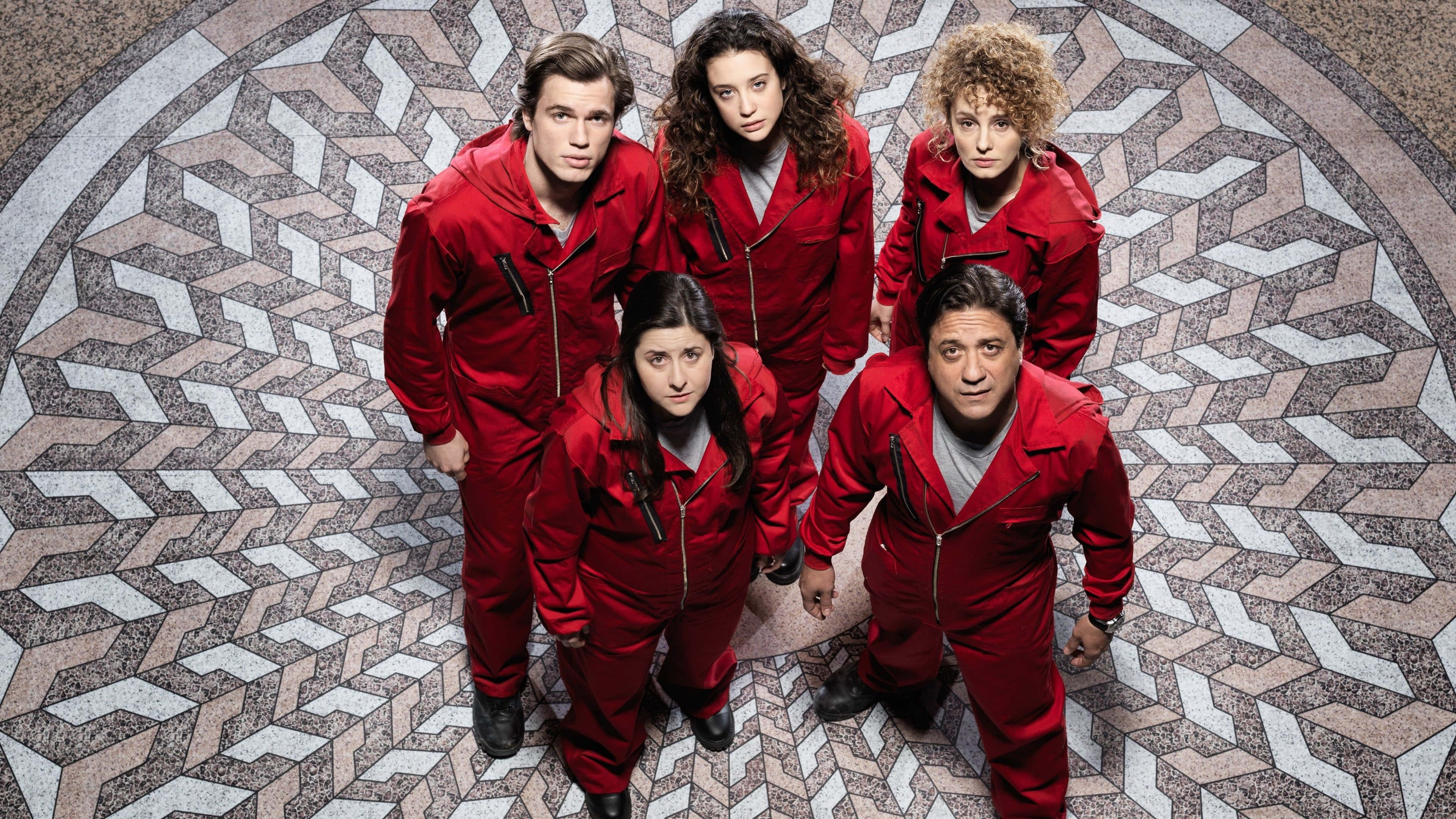 Money Heist 桌布 壁紙 — 五個身穿紅色連身衣褲的人站在幾何圖案瓷磚地板上圍成一個圓圈，表情嚴肅地向上看。