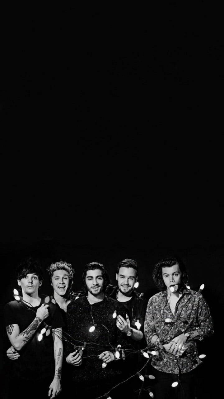 One Direction Aesthetic 桌布 壁紙 — 五個黑白打扮的男人在黑暗背景前拿著燈串擺姿勢。