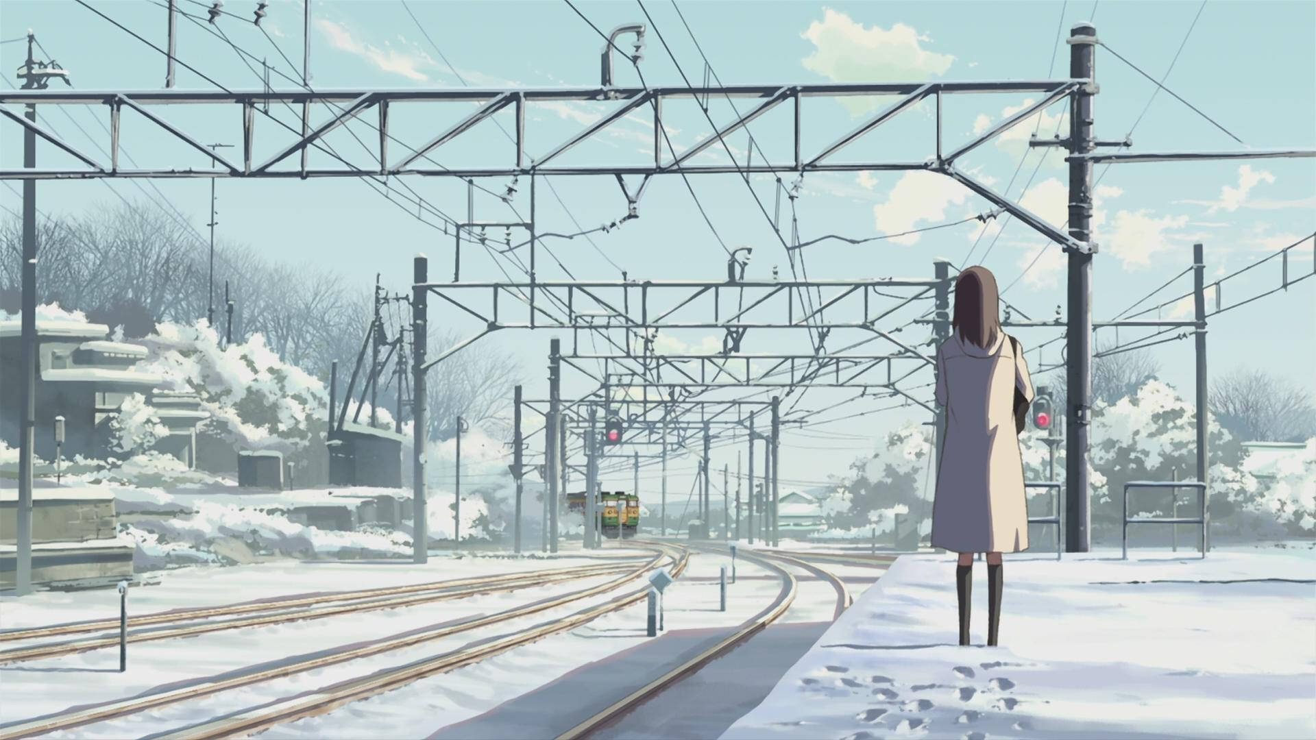 穿外套的女孩在積雪的火車站等待火車駛近軌道。