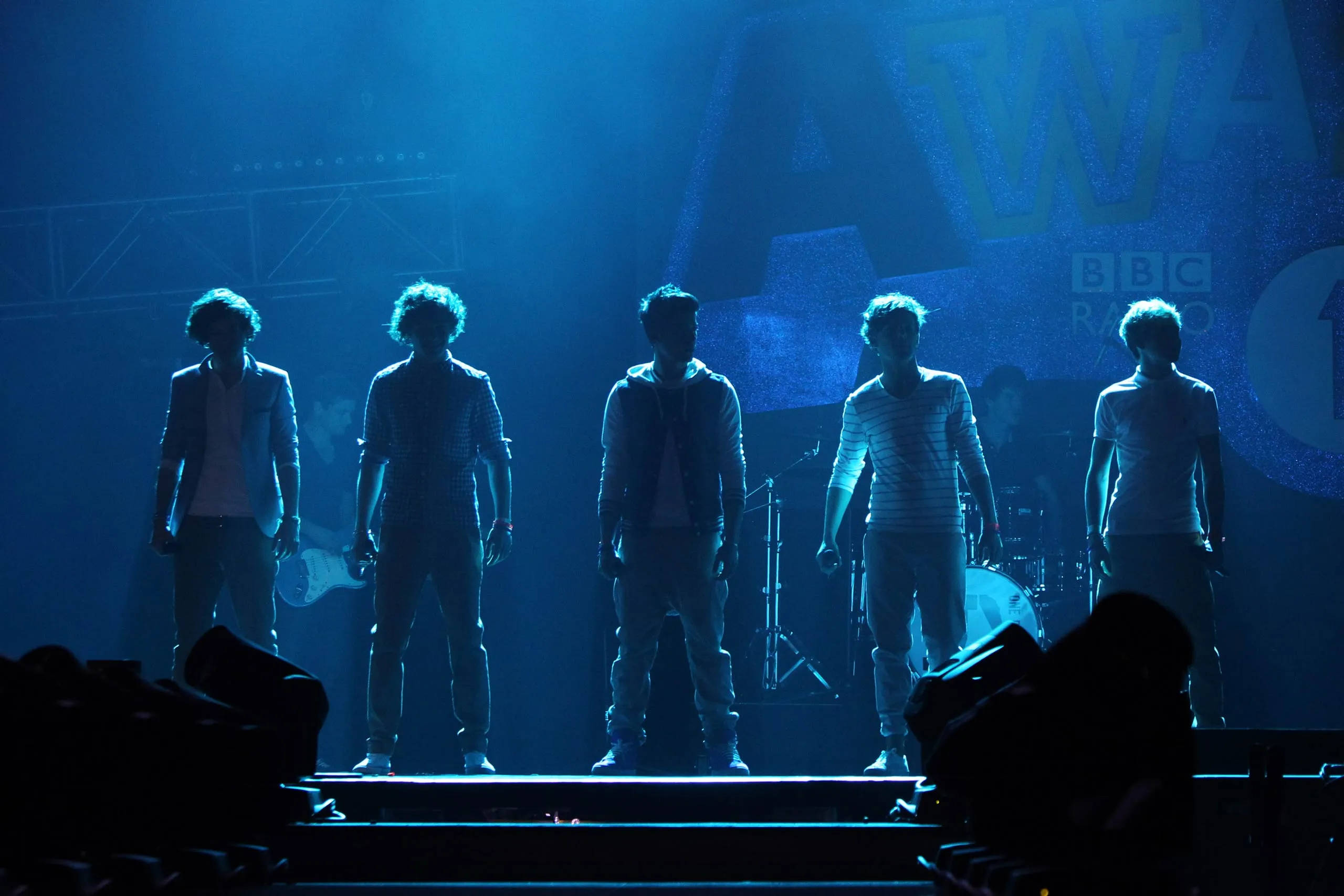 One Direction Aesthetic 桌布 壁紙 — 五名樂隊成員以剪影姿態站在一個沐浴在強烈藍光中的舞台上，背後可見BBC Radio 1標誌。