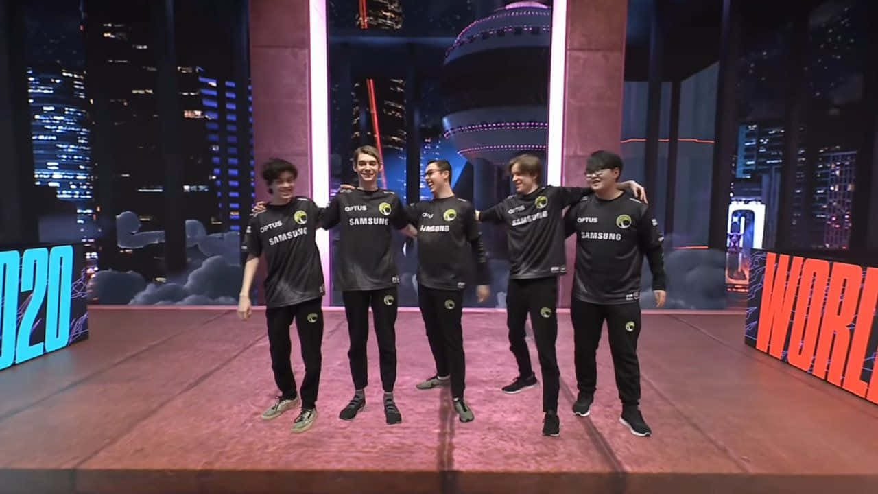 Esports 桌布 壁紙 — 五名面帶微笑的電競選手身穿黑色三星球衣，在燈光璀璨的舞台上以城市天際線為背景合影。