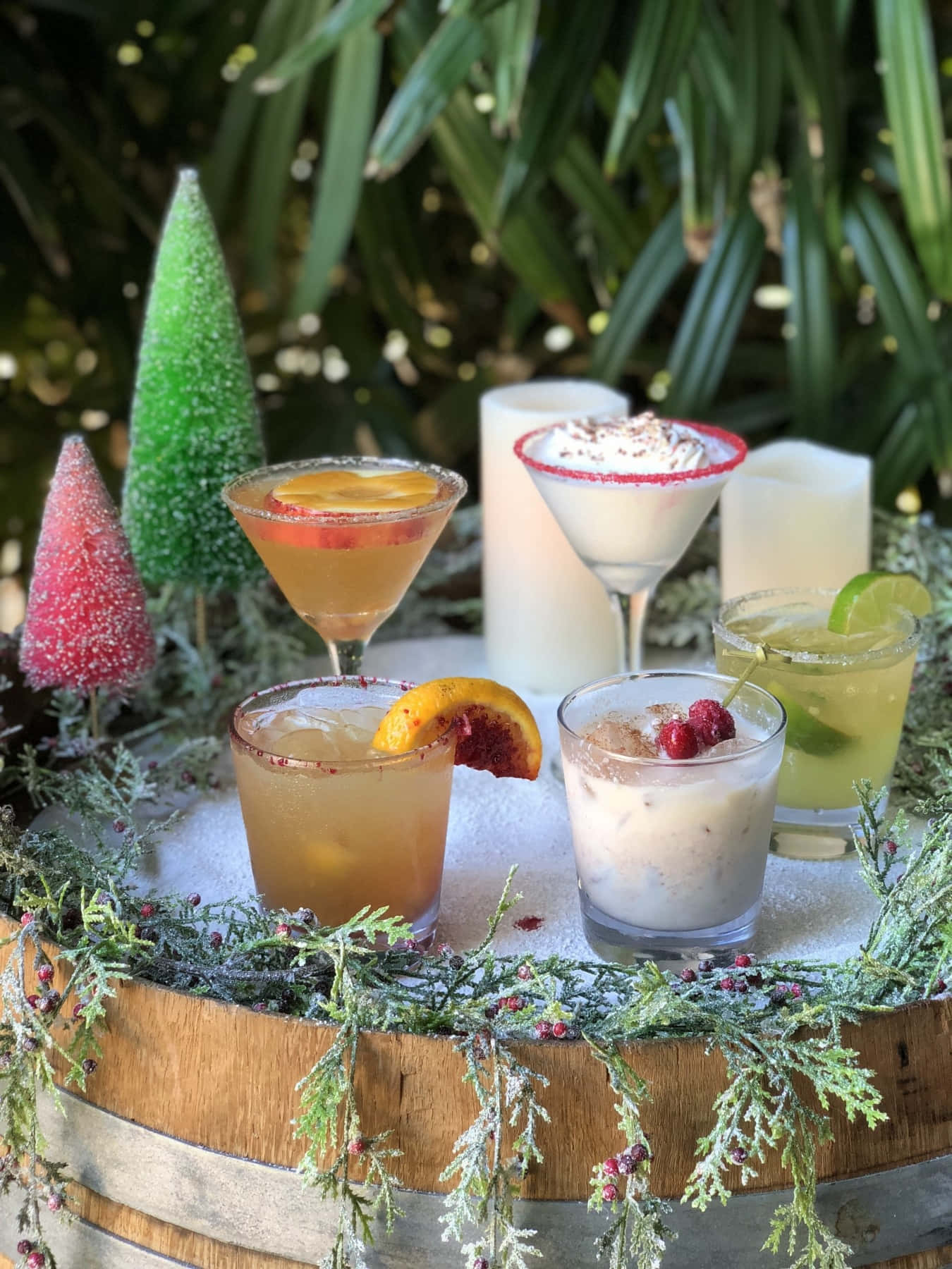 Winter Drinks 桌布 壁紙 — 五款節日雞尾酒，飾以水果和漿果，放在一個鋪滿雪的桶上，桶上裝飾著糖霜小樹和常綠花環。