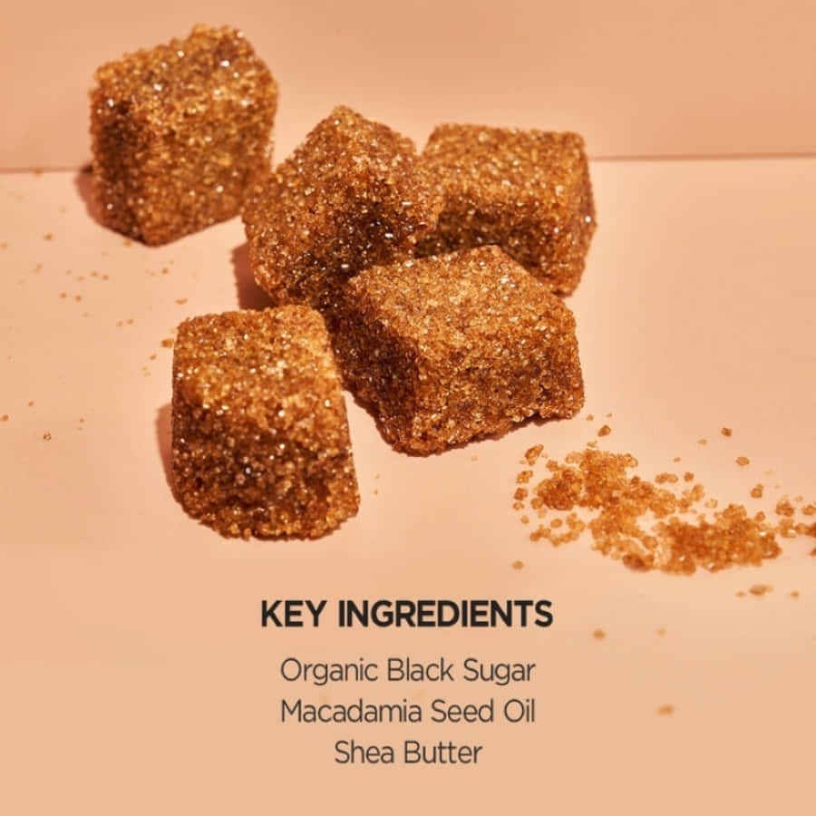 Black Sugar 桌布 壁紙 — 五粒粗糙質感的紅糖方塊，帶有散落的顆粒，在溫暖燈光下放置於柔軟的蜜桃色表面上。