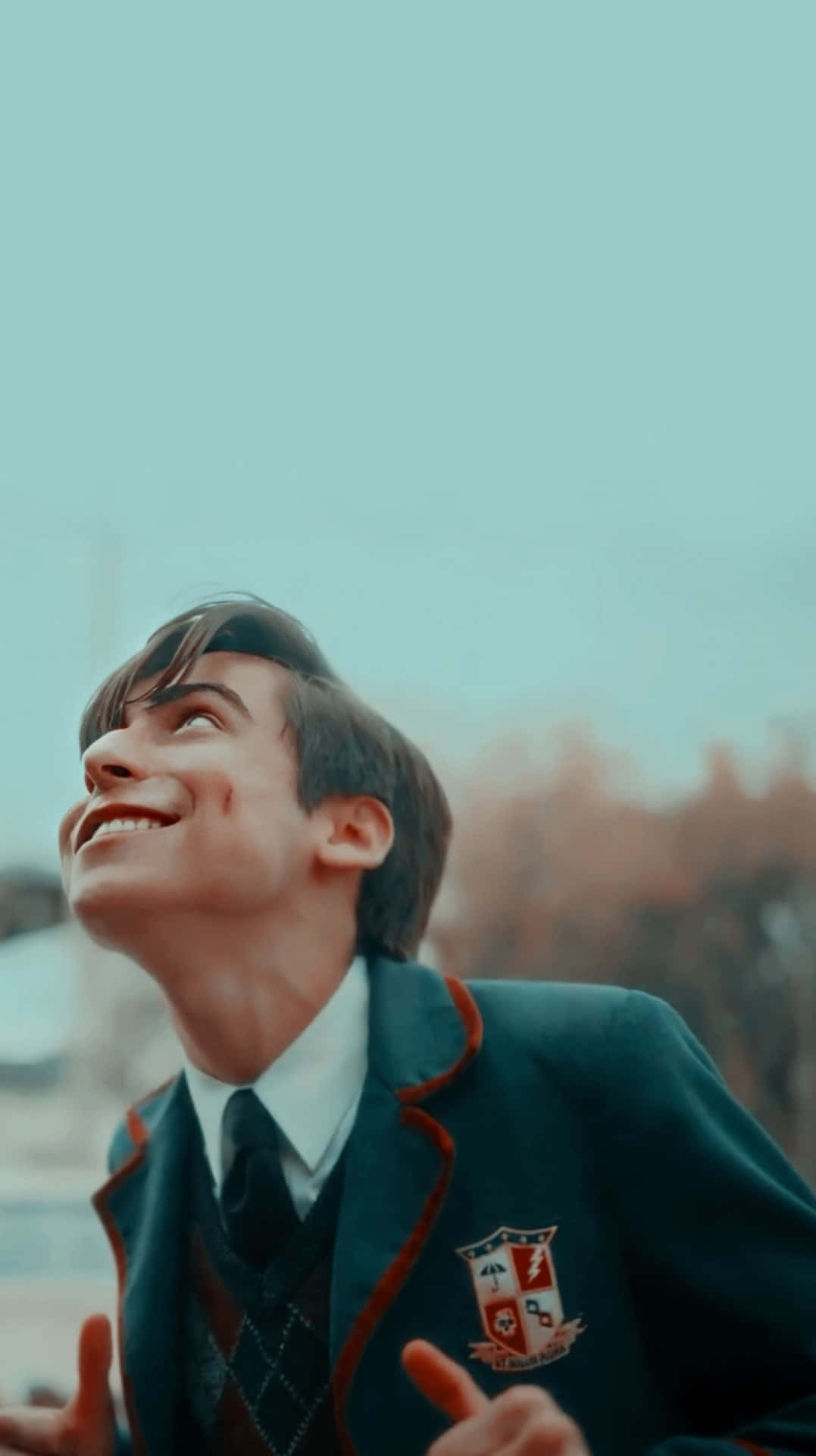 一名微笑的年輕男子穿著校服仰望天空。