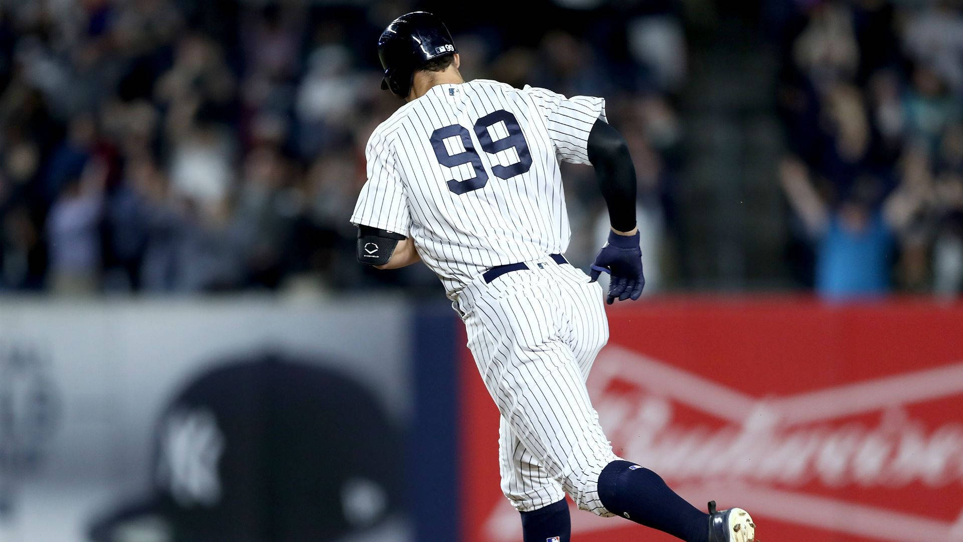 身穿細條紋球衣的棒球選手在夜間球場奔跑。